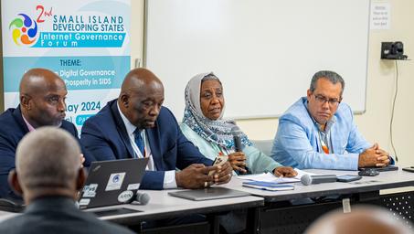 A panel of four individuals seated at a conference table, engaged in discussion.