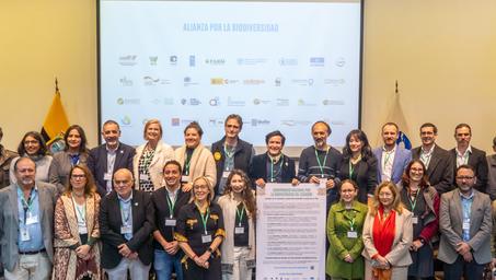Group of professionals posing together at a conference, with a presentation screen behind them.