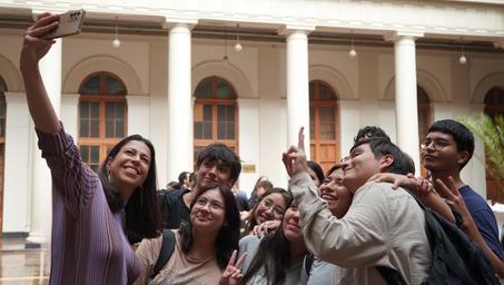A group of young people happily taking a selfie in a courtyard with columns.