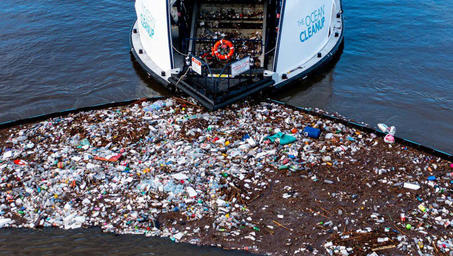 White and blue speedboat on a pebbled shoreline beside calm water; cover on water waste management.