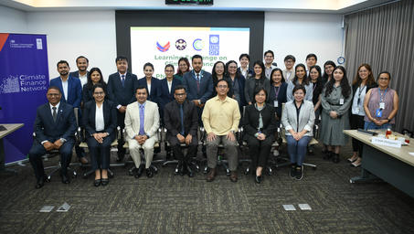 Group of professionals posing for a conference group photo in a meeting room with banners.
