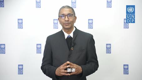 Blurred man in suit holding a small trophy at a UNDP backdrop.
