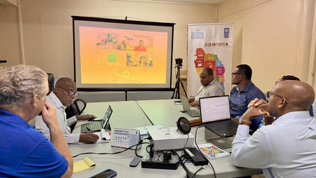 Photo: Group of colleagues around a conference table with virtual participants on the screen.