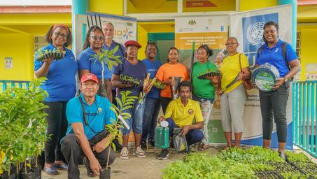 Smiling group of people posing outside a yellow building with blue columns.