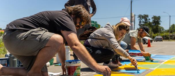 Vecinos y vecinas participan de la intervención de urbanismo táctico pintando parte de la calle
