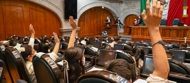 mujeres al interior de congreso levantan la mano