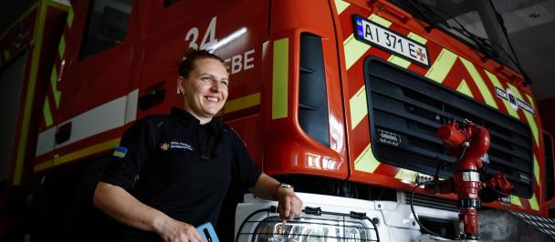 Firefighter Viktoria Kucheriava stands next to a fire truck.