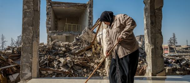 woman sleeps floor of destroyed building during Iraq reconstruction