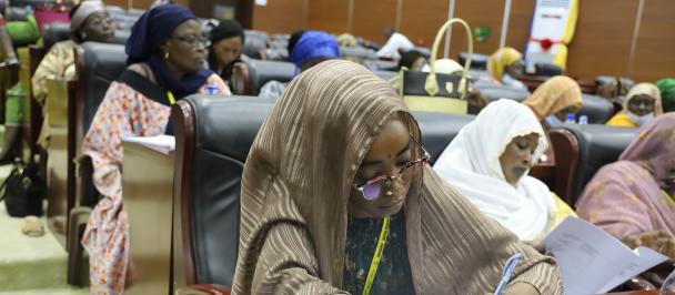 Participante prenant des notes lors de la réunion des femmes du Mécanisme de coordination dans la grande salle du Palais du 15