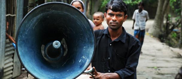 Photo of a man holding a loud speaker for early warning in Bangladesh. 