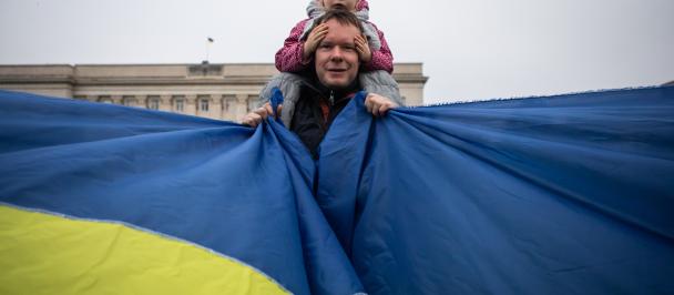 A man with a child is holding the Ukraine flag