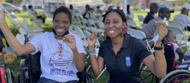 UNDP Team member poses with a happy young lady in a wheelchair at a Disabilities Week Concert and Motorcade in The Bahamas