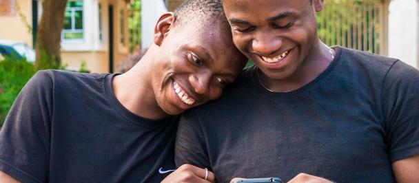 Two men smiling while looking at a mobile phone