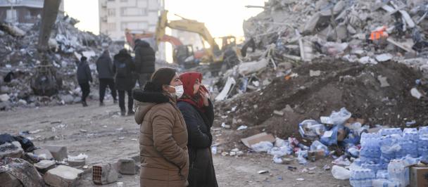 Profile view of two people surrounded by earthquake rubble