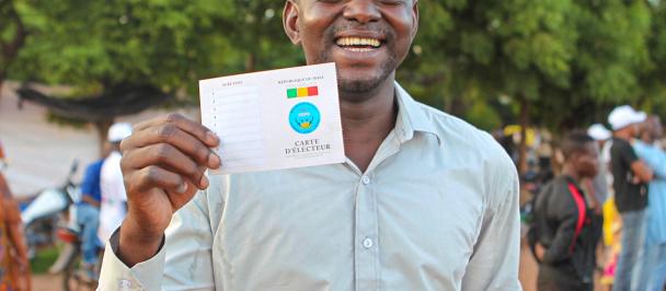 Man in light coloured shirt holds up voting card