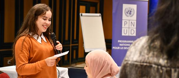 Jeune femme entrain de parler au micro devant un public jeune lors d'un workshop à djerba au sud tunisien afin de promouvoir sa région