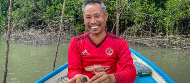 U Tun Kyaw Aung holds farmed blood clams in his hand