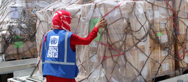Person in UNDP vest checks bundled supplies