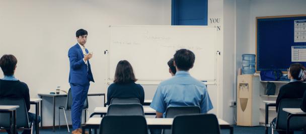 Young man in suit stands in front of white board