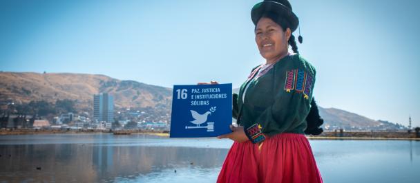 Una mujer aimara, en Puno frente al lago Titicaca, sostiene el ODS 16 Paz, Justicia e Instituciones Sólidas