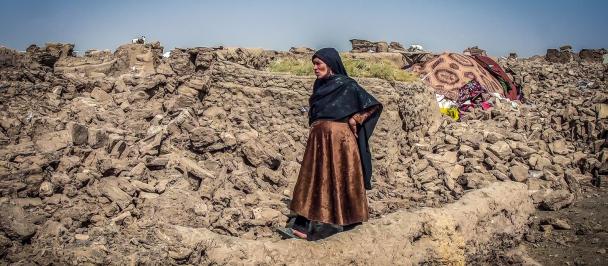 Afghanistan earthquake survivor Mahzada walks on a hillside with a makeshift tent in the background.