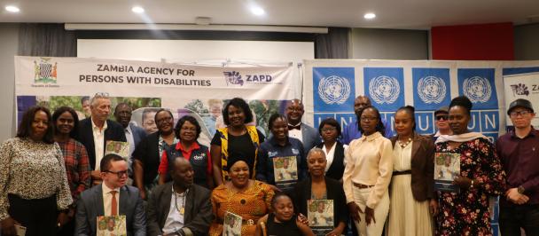Image of the Minister of Community Development and Social Services and the Director General of ZAPD, joined by the UNDP and key partners at the Launch of the ZAPD Strategic Plan. They are all holding the strategic plan