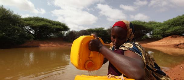 Somali woman pouring water into container