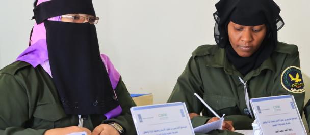 Woman in hijab sits next to woman in police uniform