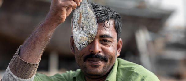 Person in a green shirt holds up a tangled string of metallic pieces outdoors.