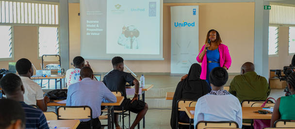 Bright classroom workshop with presenter at front, projector screen, and seated attendees.