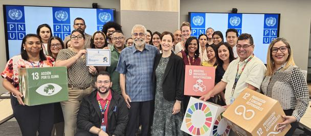 Group of diverse people posing for a photo at a workshop, holding colorful signs.