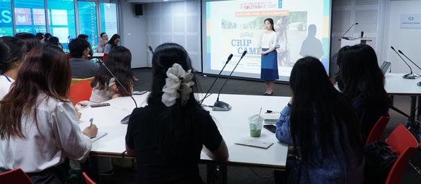 Photo of a conference room workshop with attendees watching a presenter on a screen.