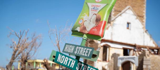 Photo: Sunlit street corner with green banner and blue street signs, North Street and West Street.