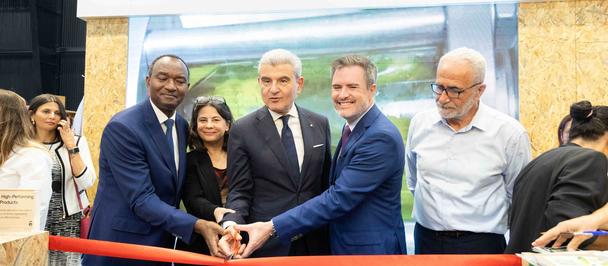 Group of officials cutting a red ribbon at a ceremony, backdrop shows Canadian and UN logos.