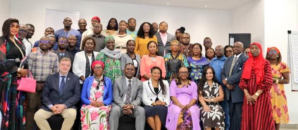 Group of diverse people posing for a photograph in a bright conference room.