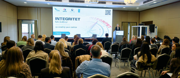 Audience seated in a conference room watching a stage presentation on integrity.