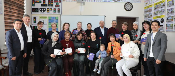 Group of adults smiling in a classroom with a whiteboard and posters.