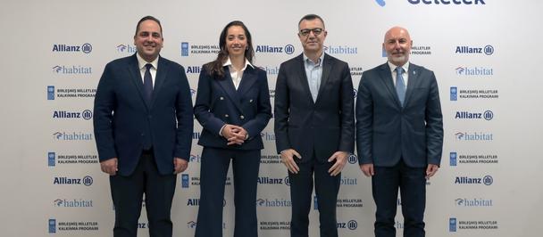 Photograph of five professionals in suits posing in front of a backdrop with Allianz logos.