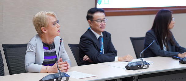 Photograph of three panelists seated at a conference table with microphones.