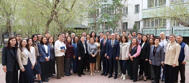 Group photo of a large group of professionals in business attire outdoors in a courtyard.