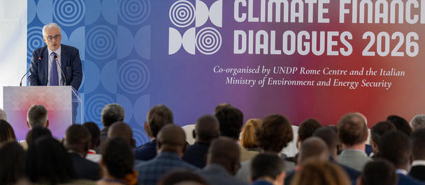 Photograph of a speaker at the Climate Dialogues 2026 conference stage with an attentive audience.
