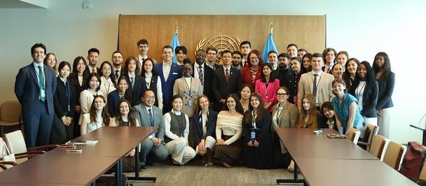 Large group of professionals posing for a group photo in a conference room around a long table.