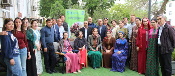 Group of people in colorful outfits posing on a green lawn outdoors.
