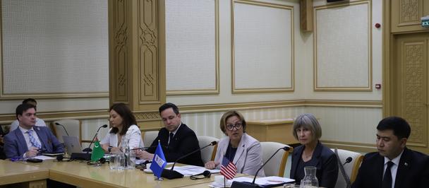 Seven professionals in business attire seated around a long conference table in a formal room