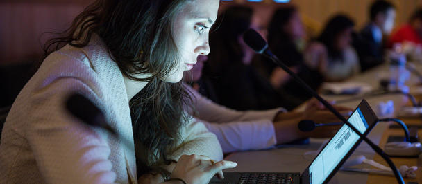 Woman with long hair using a laptop at a conference table.