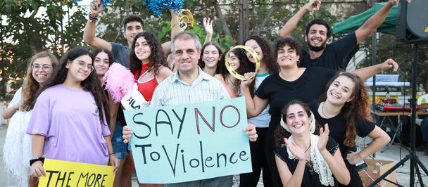 Group of diverse young people at a street event holding a sign that reads Say No To Violence.