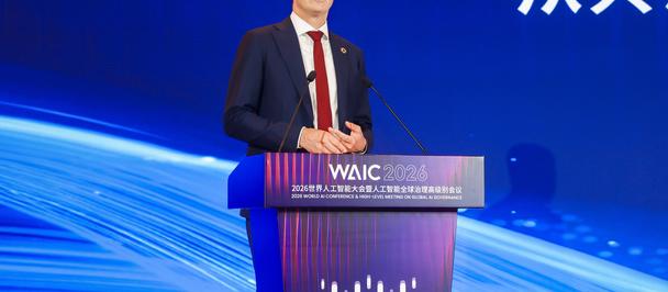 Male presenter in a suit at a WAIC podium on a blue stage with flowing light design.