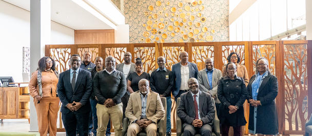Group photo of professionally dressed people posing in a bright, modern lobby.