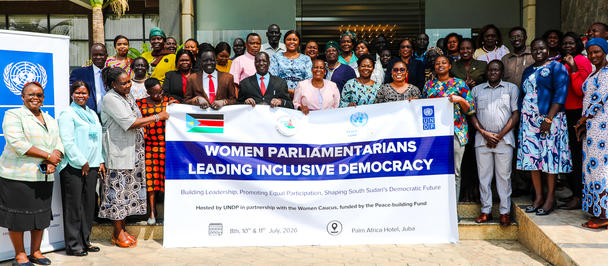 Group of people posing with a blue banner outside a building.