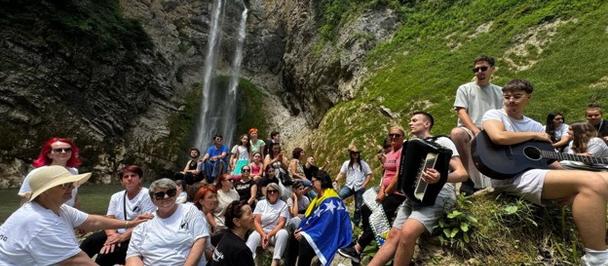Group of people posing together in a rocky canyon with a waterfall in the background.